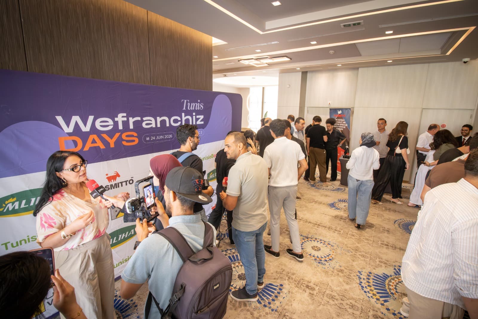 إحدى المتحدثات تُجري معها صحفي حوارًا أمام منطقة التقاط الصور في فعاليات WeFranchiz Days Tunis 2026.